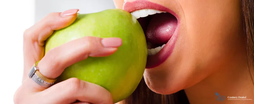 CD - A woman with healthy teeth biting into a green apple
