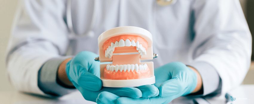 CD-Dentist holding dentures in office room